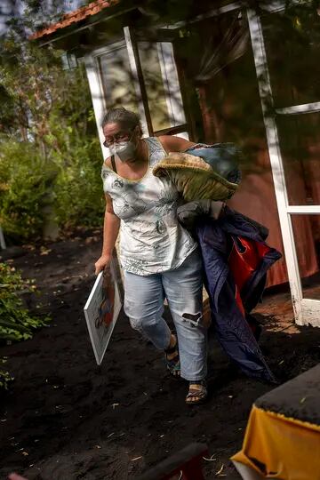 Annette Lowestein, de Alemania, recoge algunas de sus pertenencias mientras sale de su casa acechada por la lava que avanza hacia su barrio en la isla canaria de La Palma