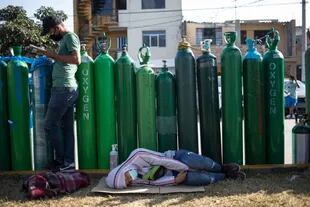 Algunas personas esperan en la fila para recargar los tanques de oxígeno, en Lima