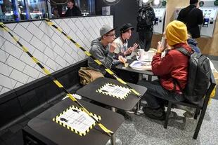 Jóvenes en un restaurante de comida rápida junto a mesas separadas en el centro de Estocolmo, el 12 de noviembre de 2020
