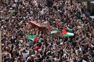 Cientos de palestinos ondean banderas nacionales mientras llevan el féretro de la periodista de Al-Jazeera asesinada, Shireen Abu Akle, durante su procesión fúnebre cerca de la Puerta de Jaffa, una de las puertas principales de la Ciudad Vieja de Jerusalén, el 13 de mayo de 2022.