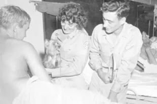 Una enfermera de la Cruz Roja sostiene a Smoky, que está a punto de hacer alguna gracia en un hospital de campaña para entretener a un soldado herido