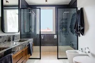 En la ducha, azulejos Acuarela ‘Iceland’ gris oscuro colocados en forma vertical. Grifería cromada ‘Dominique’ (FV).
