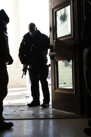 Miembros de la policía especial del Capitolio observa los daños realizados a la puerta de entrada