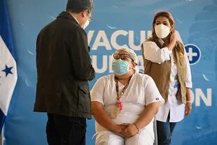 El presidente hondureño Juan Orlando Hernández habla con la enfermera Soraya Ortega antes de recibir una dosis de la vacuna de Moderna contra el Covid-19 en el Hospital María, en Tegucigalpa, el 25 de febrero de 2021