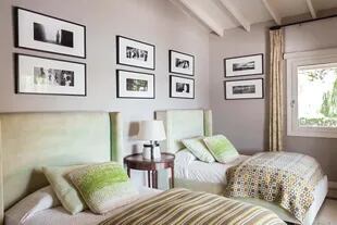En una de las habitaciones para los huéspedes, dúo de camas con respaldo tapizado (Laura O), almohadones y colchas traídos de distintos viajes y fotos de María Giménez.