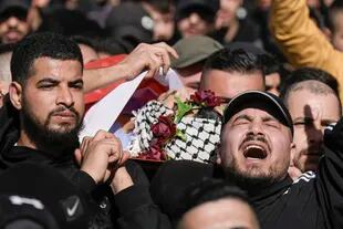 Palestinos llevan el cuerpo de Yusef Muhaisen durante su funeral en la ciudad cisjordana de al Ram, al norte de Jerusalén, el viernes 27 de enero de 2023. Muhaisen, de 22 años, murió durante los enfrentamientos con las tropas israelíes