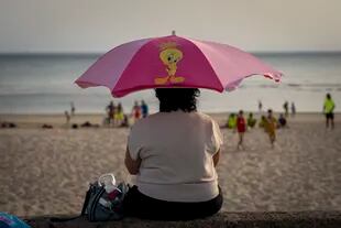 Una mujer se protege del sol bajo su sombrilla en una playa de Cádiz, España, el lunes 13 de junio de 2022