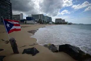 Una bandera de Puerto Rico ondea en una playa vacía en Ocean Park, el jueves 21 de mayo de 2020, en San Juan. (AP Foto/Carlos Giusti, Archivo)