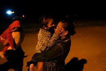 Una niña migrante de Honduras besa a su madre a través de los barbijos en un área de admisión luego de cruzar la frontera en La Joya, estado de Texas