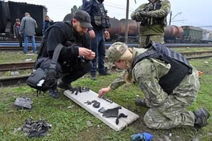 Un experto forense en explosivos y un experto de la policía recogen fragmentos de misiles después de un ataque en una estación de tren de carga en Kharkiv el 21 de septiembre de 2022, en medio de la invasión militar de Rusia en Ucrania.