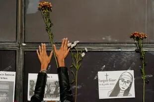 Una mujer coloca flores en la fachada de la Fiscalía General de la República durante una protesta por la desaparición de Debanhi Escobar (AP Foto/Eduardo Verdugo)