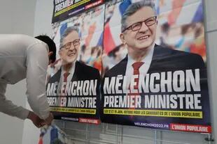 Un partidario del dirigente izquierdista Jean-Luc Melenchon coloca carteles electorales con la leyenda "Melenchon Primer Ministro" en Lille, norte de Francia, 5 de mayo de 2022