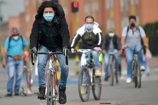 Las personas usan mascarillas como medida preventiva contra la propagación del nuevo coronavirus, mientras andan en bicicleta en Bogotá, el 29 de abril de 2020