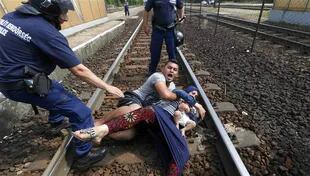 Un matrimonio de migrantes y su bebe resisten, ayer, un traslado a un campo de refugiados en las vías de una estación de Hungría