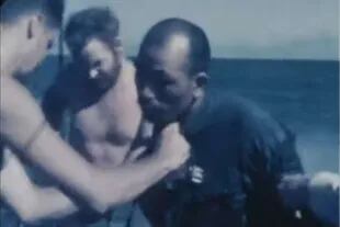 Soldados estadounidenses rescataron de una balsa a un hombre y lo revisan sobre la cubierta de un barco