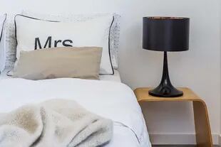 En su cuarto, la ropa de cama y los almohadones (HM Home) respetan la paleta reinante: da la nota la mesa de luz de madera (Ikea) que compró cuando vivía en París.