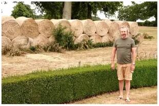 John Turner junto al muro de heno que construyó su vecino frente a su jardín.