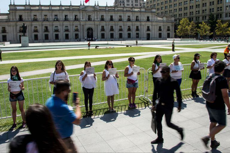 Activistas por los derechos de las mujeres sostienen letreros con información de femicidios durante una manifestación frente al palacio presidencial de La Moneda en Santiago