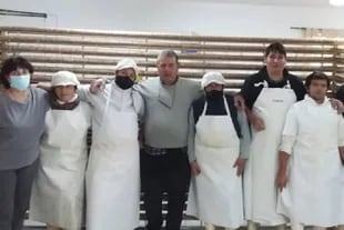 Los autores del salame más largo de la Argentina posan delante de su obra; en el centro, con pullover gris, José María Meretta