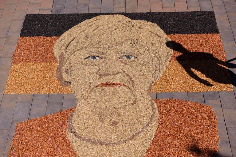 Se ve la silueta del artista kosovar Alkent Pozhegu mientras trabaja en los toques finales de una imagen hecha con grano y semilla, que representa el retrato de la canciller alemana Angela Merkel