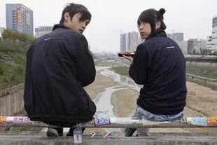 Dos trabajadores de Foxconn almuerzan en su hora de descanso fuera de la fábrica ubicada en Shenzhen, China