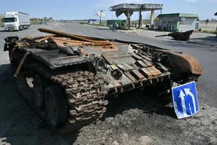 Un camiin pas por delante de los restos un tanque ruso junto a gasolinera destruida in pueblo de Skybyn, en noreste de capital ucraniana, Kiev, el 2 de mayo 2022.