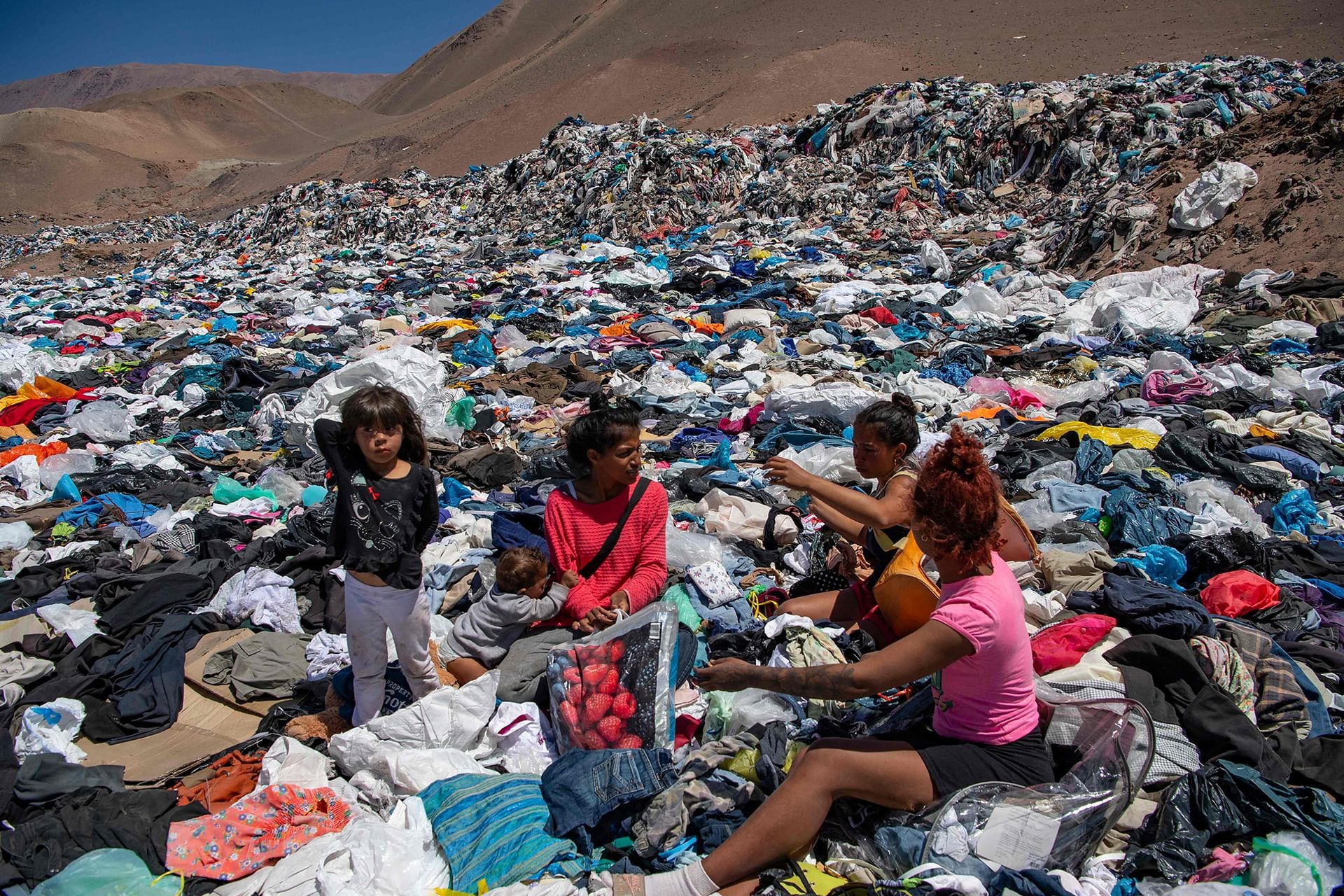 Varias mujeres revuelven la montaña de ropa desechada