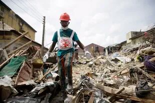Rescatistas buscan a sobrevivientes en el lugar en donde se derrumbó un edificio de tres palntas en Ebutte-Metta, en Lagos, Nigeria, el lunes 2 de mayo de 2022. (AP Foto/Sunday Alamba)