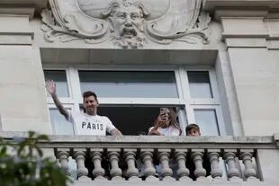 Lionel Messi saluda a sus seguidores desde el balcón de su hotel mientras su esposa, Antonella Roccuzzo, toma fotografías, en París, el 10 de agosto de 2021