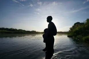 Un padre carga a su hija al ingresar a aguas del Río Bravo rumbo a Del Rio, Texas (AP Foto/Fernando Llano, archivo)