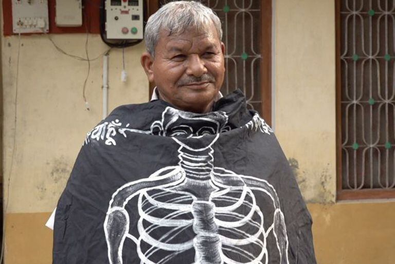 Lal Bihari Mritak envuelto en una pancarta de la Asociación de Muertos Vivientes.