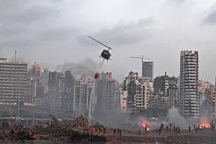 Un helicóptero intenta apagar varios incendios en la escena de la explosión masiva