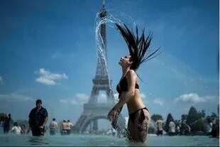 Una mujer se refresca en la fuente de Trocadero de la torre Eiffel