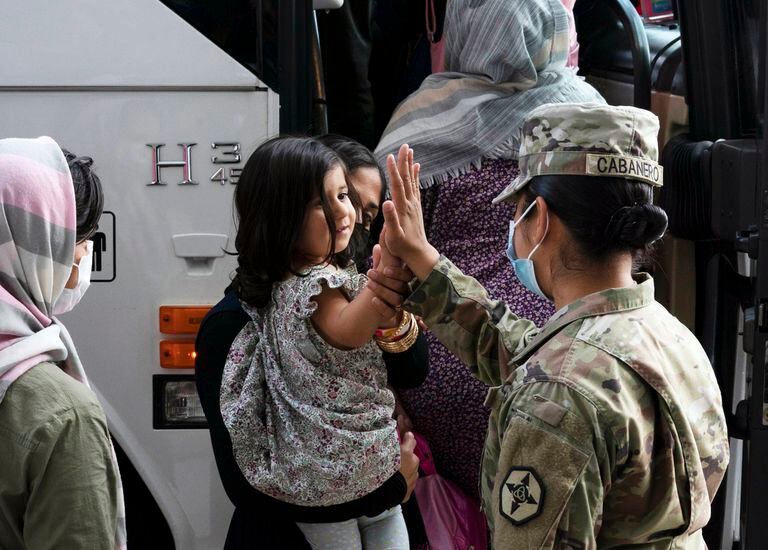Kimberly Hernandez choca los cinco con una niña evacuada de Kabul, Afganistán, antes de abordar un autobús después de su llegada al Aeropuerto Internacional Washington Dulles, en Chantilly, Virginia