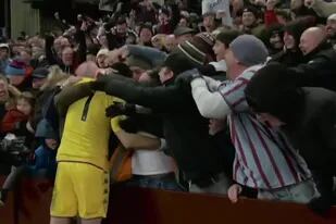 Emiliano Martínez se abraza con un grupo de hinchas luego del partido que disputaron el Aston Villa y el Manchester United.