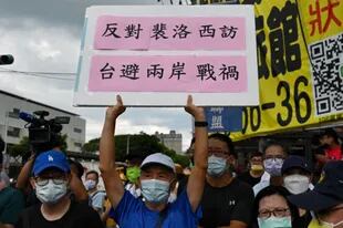 Un activista a favor de la unificación de Taiwán y China muestra una pancarta en la que se lee que se oponen a la visita de Pelosi para evitar la guerra entre dos orillas, mientras la caravana de la presidenta de la Cámara de Representantes de Estados Unidos, Nancy Pelosi, llega al parque conmemorativo del terror blanco de Jing-Mei en la ciudad de Nuevo Taipei el 3 de agosto de 2022.
