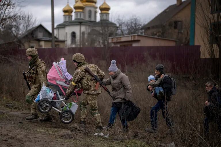 Soldados Ukranians ayudan a familia que huye a cruzar el río Irpin en las afueras de Kiev, Ukrania, sábado 5 March 2022.