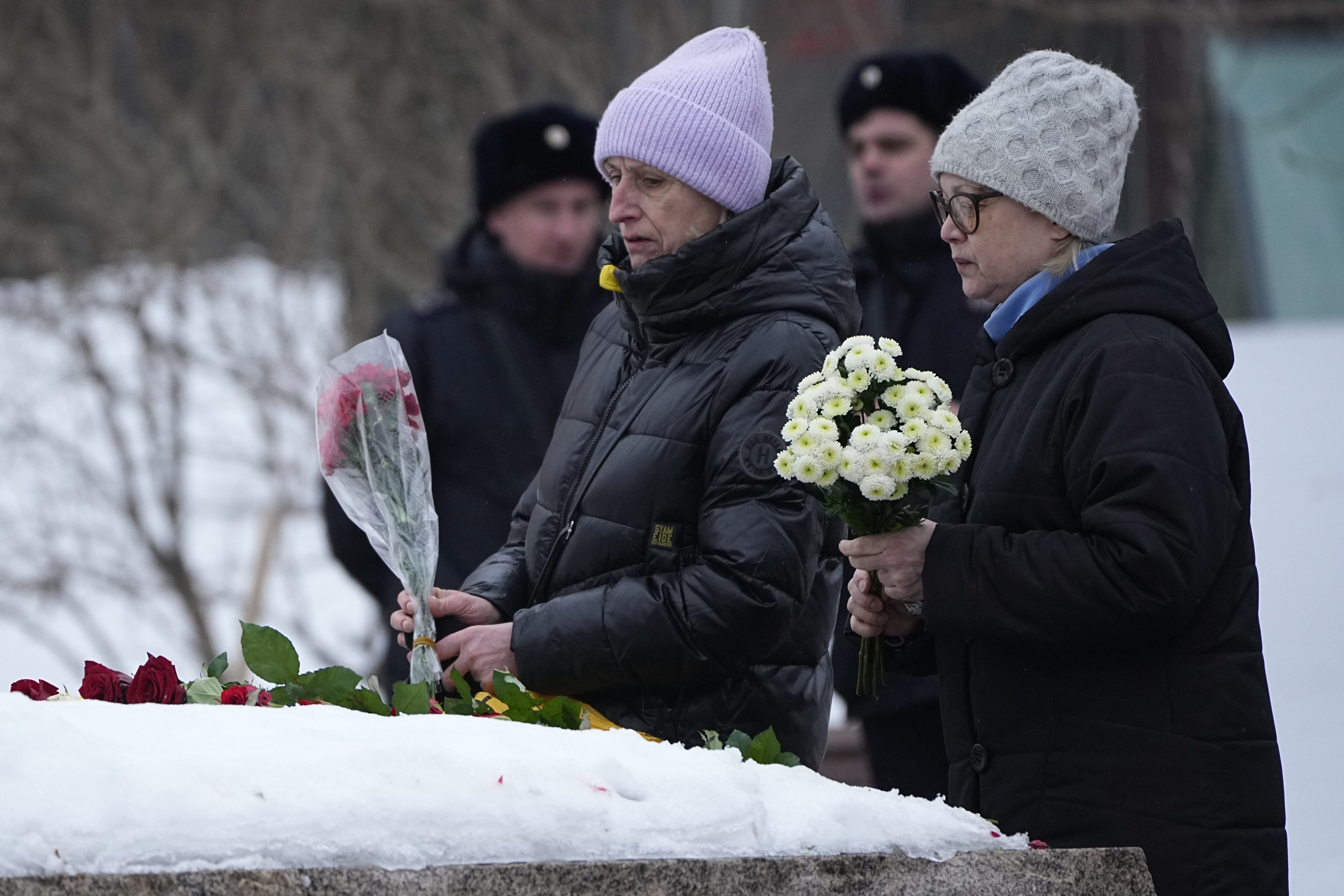 Las mujeres depositan flores para rendir homenaje a Alexei Navalny en el monumento, una gran roca de las islas Solovetsky, donde se estableció el primer campo del sistema de prisiones políticas Gulag, cerca del histórico edificio del Servicio Federal de Seguridad (FSB, sucesor de la KGB soviética) en Moscú, Rusia, el 24 de febrero 