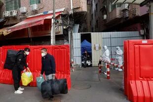 Trabajadores con sus pertenencias abandonan un pueblo con barricadas tras la relajación de las autoridades de las restricciones del COVID-19 en el distrito de Haizhu en Guangzhou, en la provincia de Guangdong, en el sur de China, el viernes 2 de diciembre de 2022.