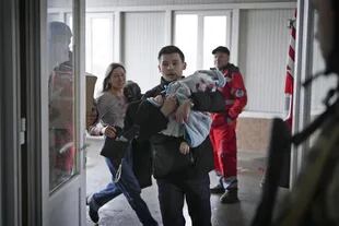 Marina Yatsko, a la izquierda, corre detrás de su novio Fedor cargando a su hijo Kirill, de 18 meses, que resultó mortalmente herido en un bombardeo, mientras llegan a un hospital en Mariupol, Ucrania, el 4 de marzo de 2022.