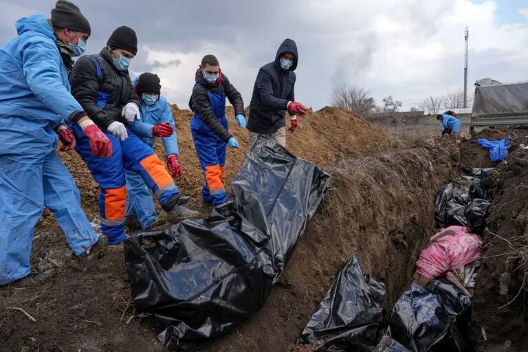 ARCHIVO - Los cuerpos son colocados en fosas comunes en las afueras de Mariupol, Ucrania, el miércoles 9 de marzo de 2022, ya que las personas no pueden enterrar a sus muertos debido a los fuertes bombardeos de las tropas rusas.  (Foto AP/Evgeniy Maloletka, archivo)