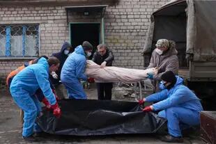 Trabajadores de una morgue trasladan un cadáver a una bolsa de plástico en las afueras de Mariupol, Ucrania, el miércoles 9 de marzo de 2022