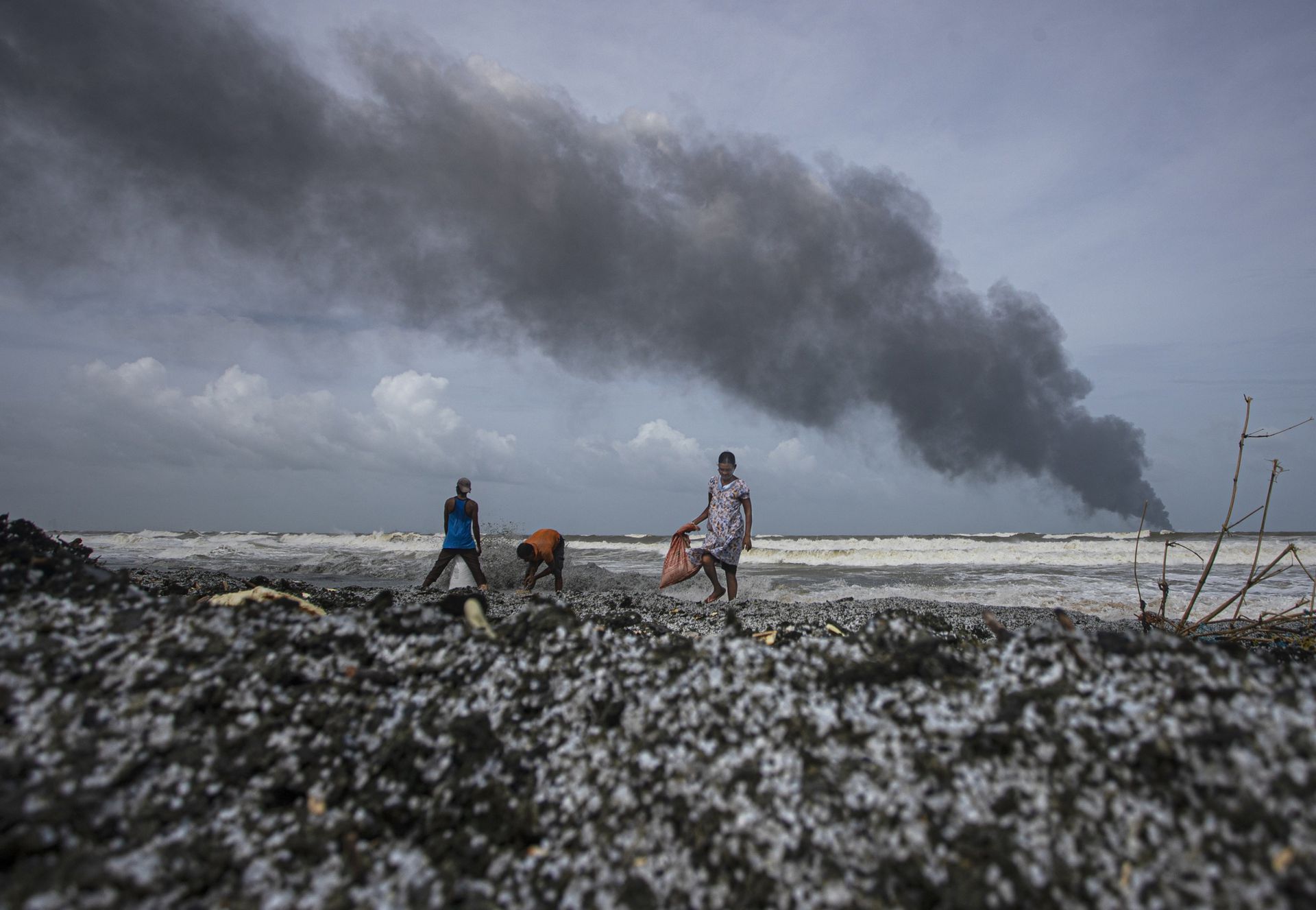 Alcune persone stanno cercando di salvare cose tra i resti cremati che raggiungono la costa dello Sri Lanka