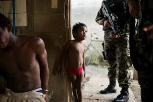 Testigos de la violencia. Un chico observa cómo esposan a un hombre, en medio de la investigación por un asesinato en San Pedro Sula, la ciudad más violenta del mundo fuera de una zona de guerra