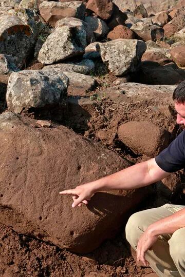 Barak Tzin, arqueólogo de la Autoridad de Antigüedades de Israel (IAA), dirige las excavaciones y muestra una rara piedra grabada tallada con dos figuras con cuernos y brazos extendidos