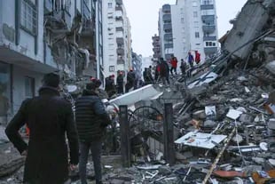 Las personas y los equipos de rescate intentan llegar a los residentes atrapados dentro de los edificios derrumbados en Adana, Turquía