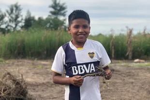 Nehuel Rivero ayuda a su papá a limpiar la tierra de la huerta comunitaria en la que trabaja