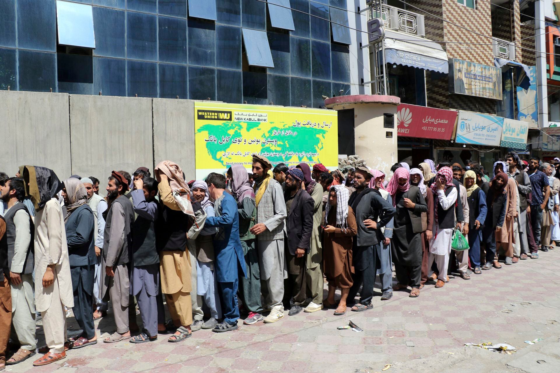 Afganos esperan frente al Kabul Bank, en Kabul. Los talibanes recuperaron el control de Afganistán casi 20 años después de que fueron derrocados en una invasión liderada por Estados Unidos tras los ataques del 11 de septiembre. Su regreso al poder ha empujado a muchos afganos a huir, por temor a represalias de los combatientes o un regreso al brutal gobierno que impusieron la última vez que gobernaron el país