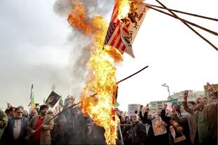 Manifestantes queman la bandera de Estados Unidos durante una manifestación a favor del gobierno después de las protestas por el aumento en el precio del combustible