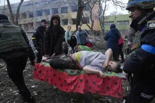 Empleados y voluntarios de emergencia ucranianos llevan a una mujer embarazada herida desde el hospital de maternidad dañado por los bombardeos en Mariupol, Ucrania, el miércoles 9 de marzo de 2022